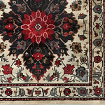 Close-up view of the Timeless Floral Medley Hand Knotted Wool Rug, showcasing intricate floral patterns in vibrant red and black tones on a beige background. Ideal for adding a touch of elegance to your living room or office, this vintage Persian-style area rug is perfect for those seeking 8x10 living room rugs.