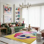 Modern living room with a green sofa, colorful rug, and abstract art.