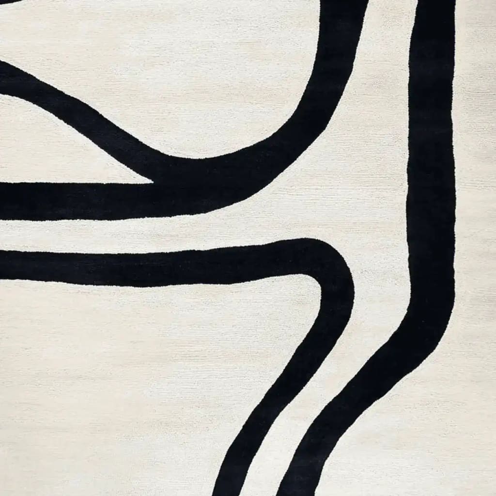 Close-up view of the Trace Lines Hand Tufted Rug showcasing its contemporary design. This wool area rug features bold black abstract lines on a neutral background, making it an ideal choice for a stylish living room.
