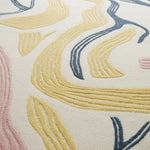 Close-up of a textured rug with wavy patterns in yellow, blue, and pink on a neutral background.