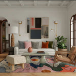A vibrant and contemporary Area Rug in a large living room setting. The wool rug features an abstract design with colorful patterns, adding a modern touch to the decor. It complements the cozy seating area with a white sofa, patterned cushions, and a stylish coffee table. Ideal for those seeking area rugs for living room or office spaces.