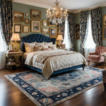 Luxurious bedroom with a blue upholstered bed, ornate chandelier, and decorative rug.