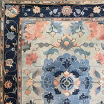 Close-up of the Tranquil Tapestry Hand Tufted Rug showcasing its intricate floral design. This elegant area rug, perfect for dining rooms and bedrooms, features a harmonious blend of soft wool with vibrant colors in a floral pattern, ideal for enhancing any dining room or bedroom space.