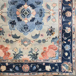 Top view of the Tranquil Tapestry Hand Tufted Area Rug, showcasing an intricate floral design in soothing blue and peach tones. This wool rug is perfect for adding elegance to dining room or bedroom spaces.