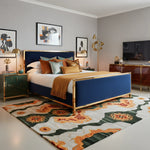 Modern bedroom with a blue bed, gold accents, an abstract wool rug, and abstract art on the wall.