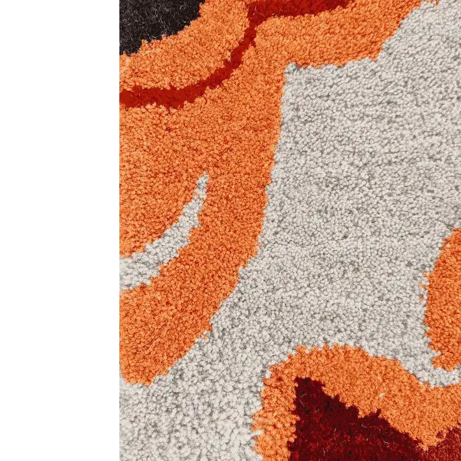 Close-up view of a vibrant hand-tufted tribal tapestry area rug, featuring bold orange, white, and black abstract patterns. Perfect for dining rooms or offices, this wool rug adds a contemporary touch to dining room carpets.