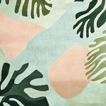 A vibrant area rug showcasing a tropical bloom design with abstract leaf patterns in shades of green and blush. This contemporary rug, perfect for large living rooms, is hand-tufted from high-quality wool, adding a touch of elegance and nature-inspired charm.