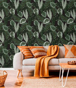 Tropical botanical leaf wallpaper above gray sofa styled with terracotta cushions and amber throw