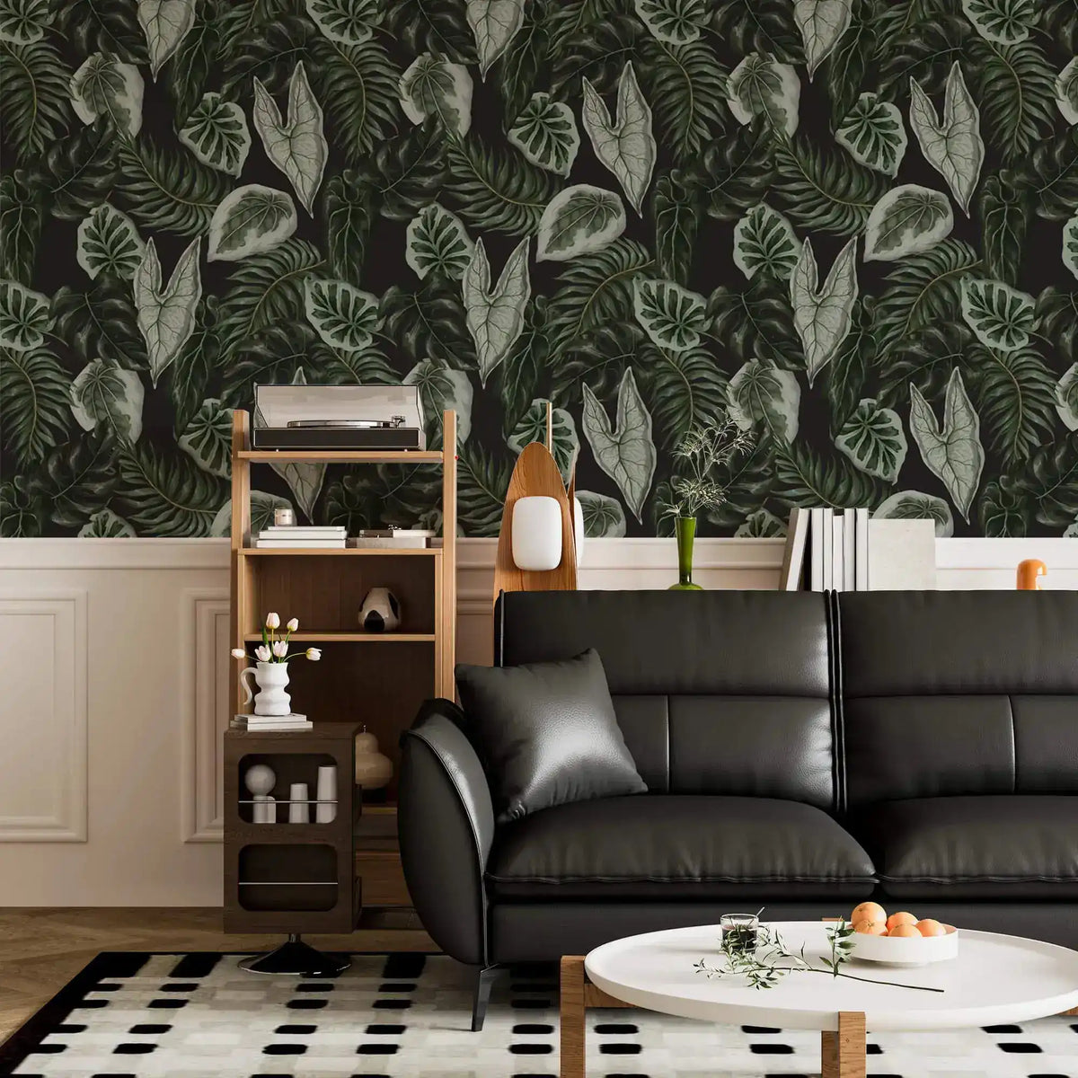 Tropical botanical leaf wallpaper above white wainscot with black leather sofa and shelving unit