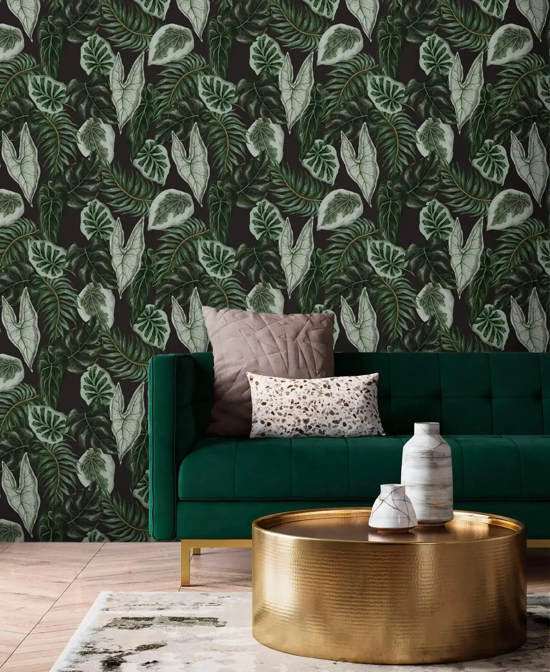 Tropical botanical leaf wallpaper behind emerald velvet sofa and gold drum coffee table