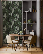 Tropical botanical leaf wallpaper in dining nook with round wood table, cream chairs and gray shelving