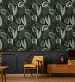 Tropical botanical leaf wallpaper over dark panel wall with yellow midcentury chair and walnut sideboard