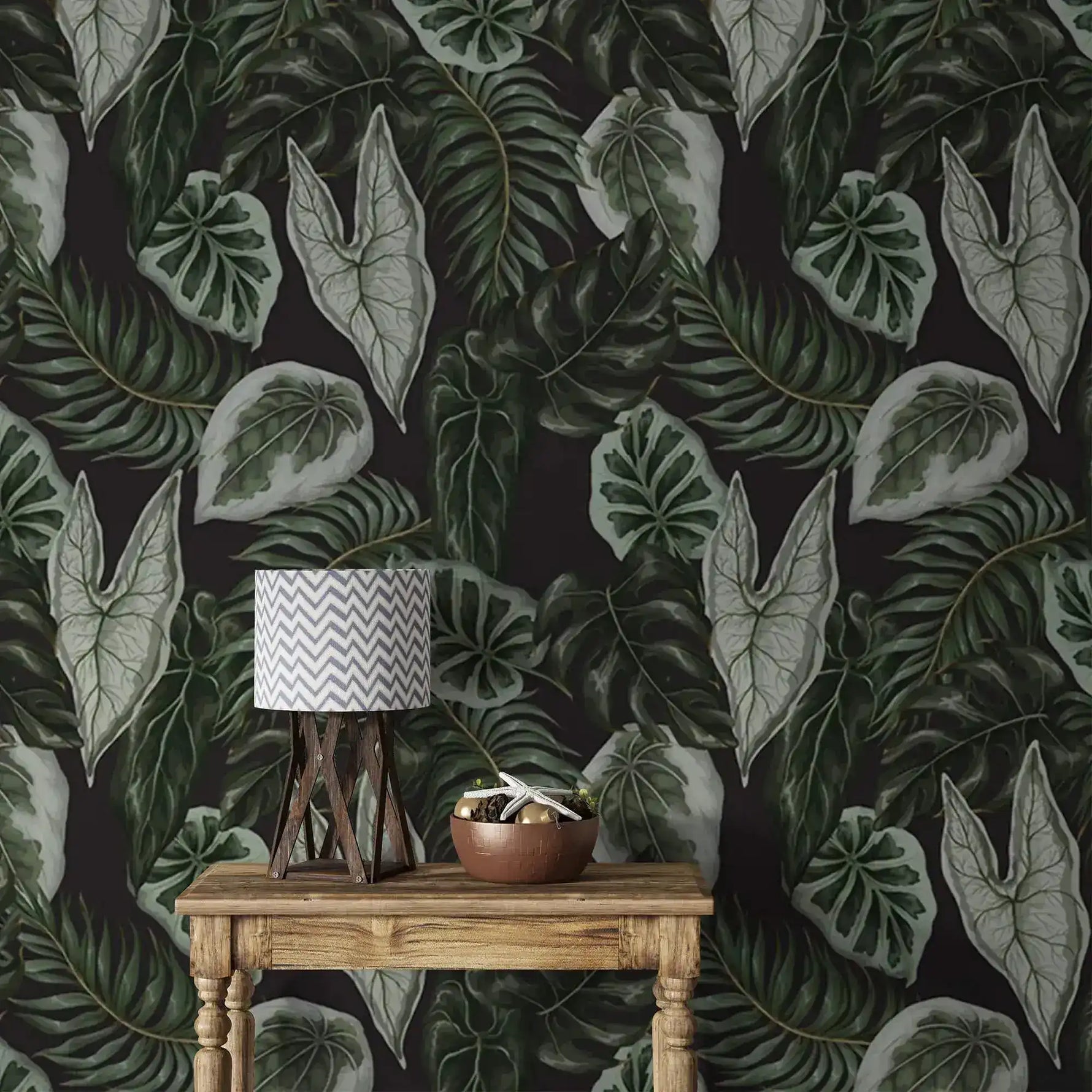 Tropical botanical wallpaper close view, large green leaves on dark wall with rustic table and lamp