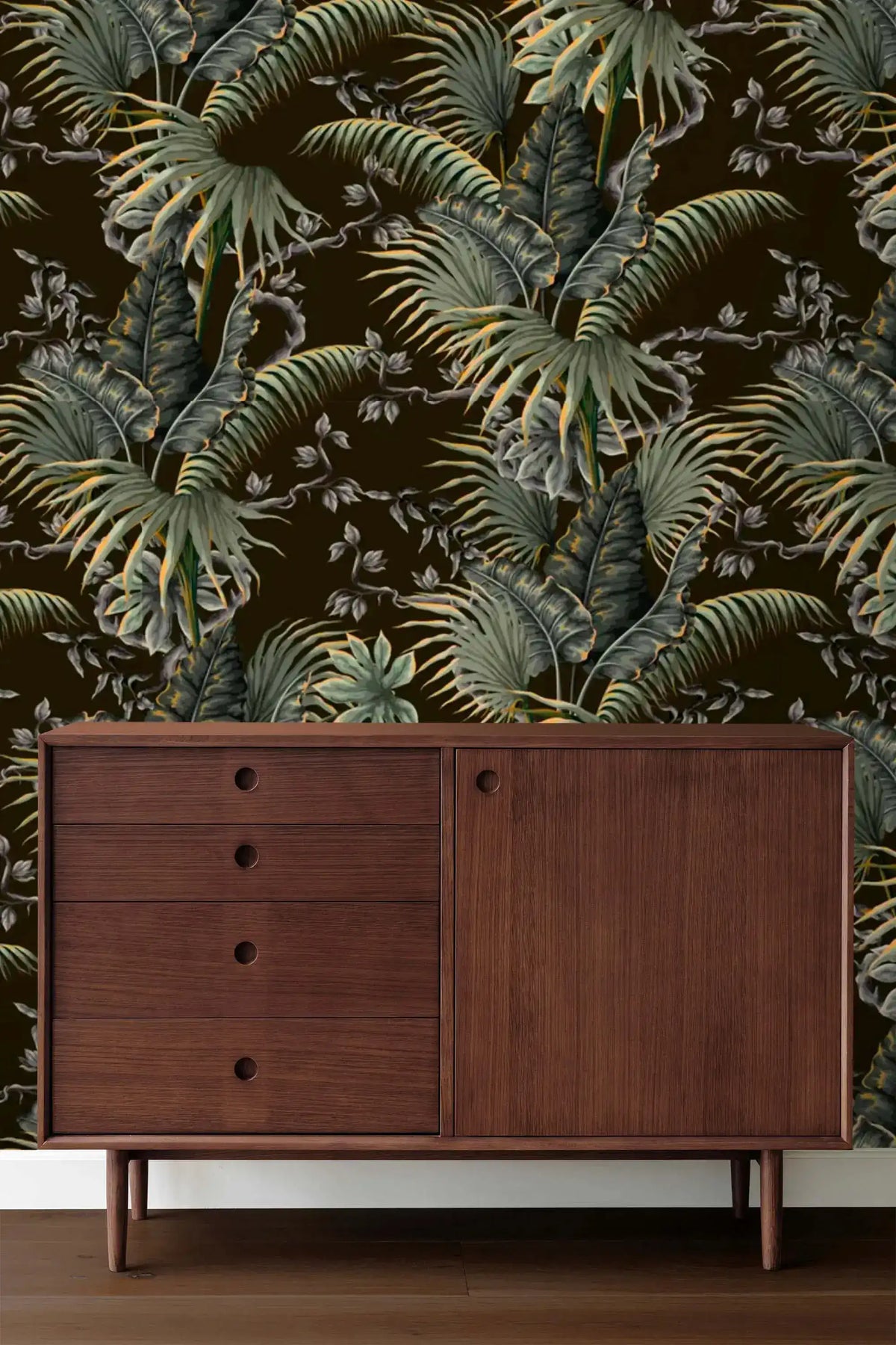 Tropical canopy wallpaper with green palm fronds on a dark ground above a walnut mid-century sideboard