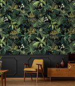 Tropical jungle canopy wallpaper over dark wainscot with yellow midcentury chair and walnut sideboard