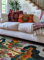 A vibrant Tropical Oasis Hand Tufted Area Rug in a living room setting. The wool rug features a colorful abstract design with tropical plant motifs, complementing the cozy white sofa adorned with decorative pillows. Ideal as a square area rug for living rooms, this 8x10 rug enhances the space with its exotic flair.