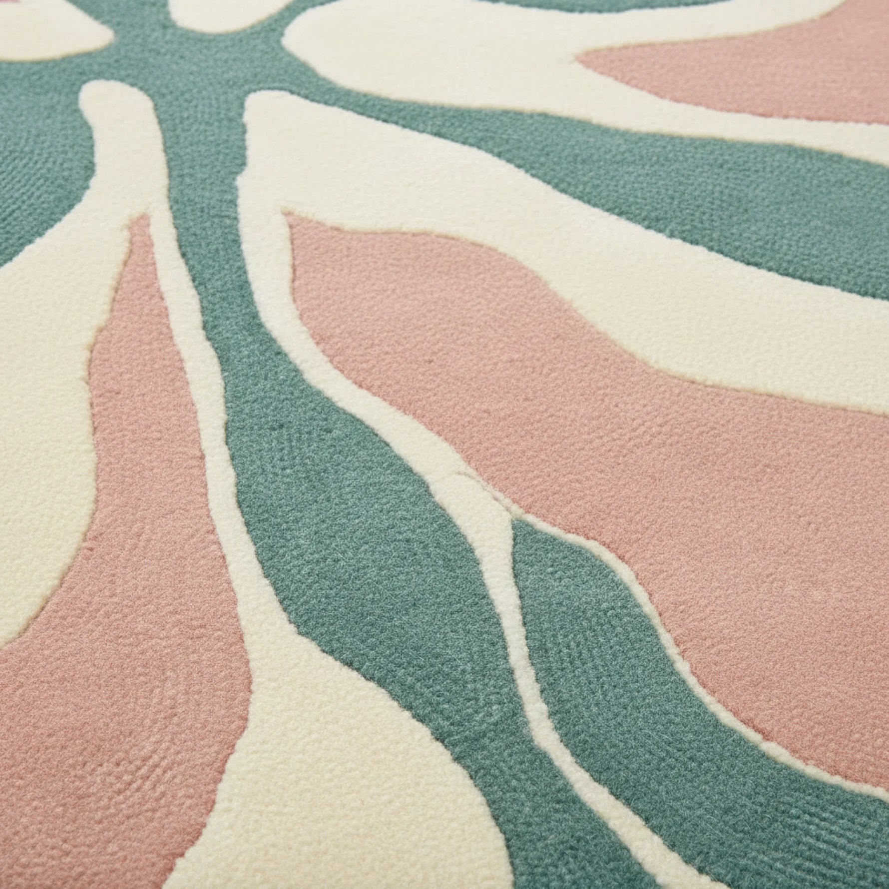 Close-up of a patterned rug with pink, green, and beige colors.