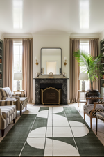 Living room with a fireplace, patterned rug, and striped chairs.