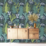 Underwater Flora Wallpaper of green seaweed and white coral on teal behind a wood sideboard