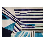 A vibrant hand-tufted area rug featuring dynamic stripes in shades of blue, black, and white. This contemporary rug is perfect for adding a modern touch to living room decor. Made from high-quality wool, it is one of the ideal rugs for living rooms, offering both style and comfort.