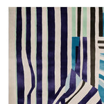 A contemporary area rug with bold, vertical stripes in shades of navy, teal, and black against a cream background. This wool rug, perfect for adding a modern touch to any living room, is a striking example of living room area rugs that combine style and functionality.