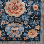 Close-up of the Verdant Tapestry Hand Tufted Area Rug, showcasing intricate floral patterns with vibrant orange and blue hues, ideal for adding a vintage touch to dining room decor. This wool rug combines elegance and practicality, making it a perfect choice for dining room area rugs.