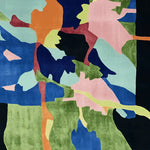 Top view of the Verdant Terrain Collage Hand Tufted Rug showcasing its vibrant abstract design. This contemporary wool area rug features a dynamic mix of blues, greens, pinks, and oranges, making it an ideal centerpiece for large living room spaces.