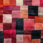 Top view of the Vermilion Grid Hand Tufted Area Rug, showcasing a vibrant patchwork of red, orange, and black hues. This contemporary wool rug is perfect for adding a bold touch to a living room. Ideal for those seeking large area rugs to enhance their space.