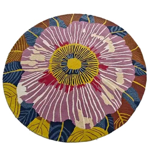 A vibrant, hand-tufted round area rug featuring a striking floral design with a large central bloom in pink, accented by yellow, blue, and brown petals. This wool rug is perfect for adding a splash of color and style to your dining room or office space.