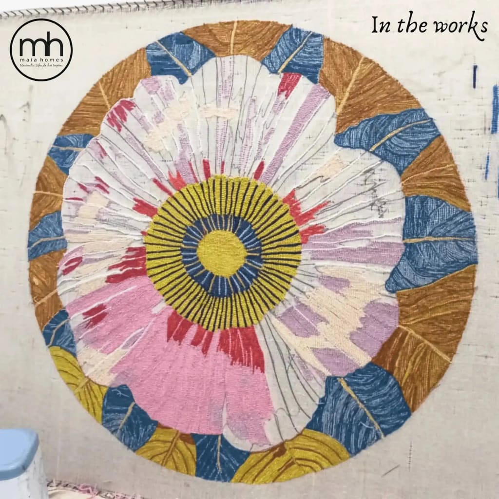 A vibrant round area rug featuring a hand-tufted floral design in progress, showcasing bold pink, yellow, and blue hues. Perfect for adding a splash of color to dining rooms or as an eye-catching wool rug in office spaces.