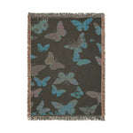 Vibrant Butterfly Woven Blanket charcoal-dark reverse side showing teal and gray-purple butterfly silhouettes woven on dark ground with fringed edges