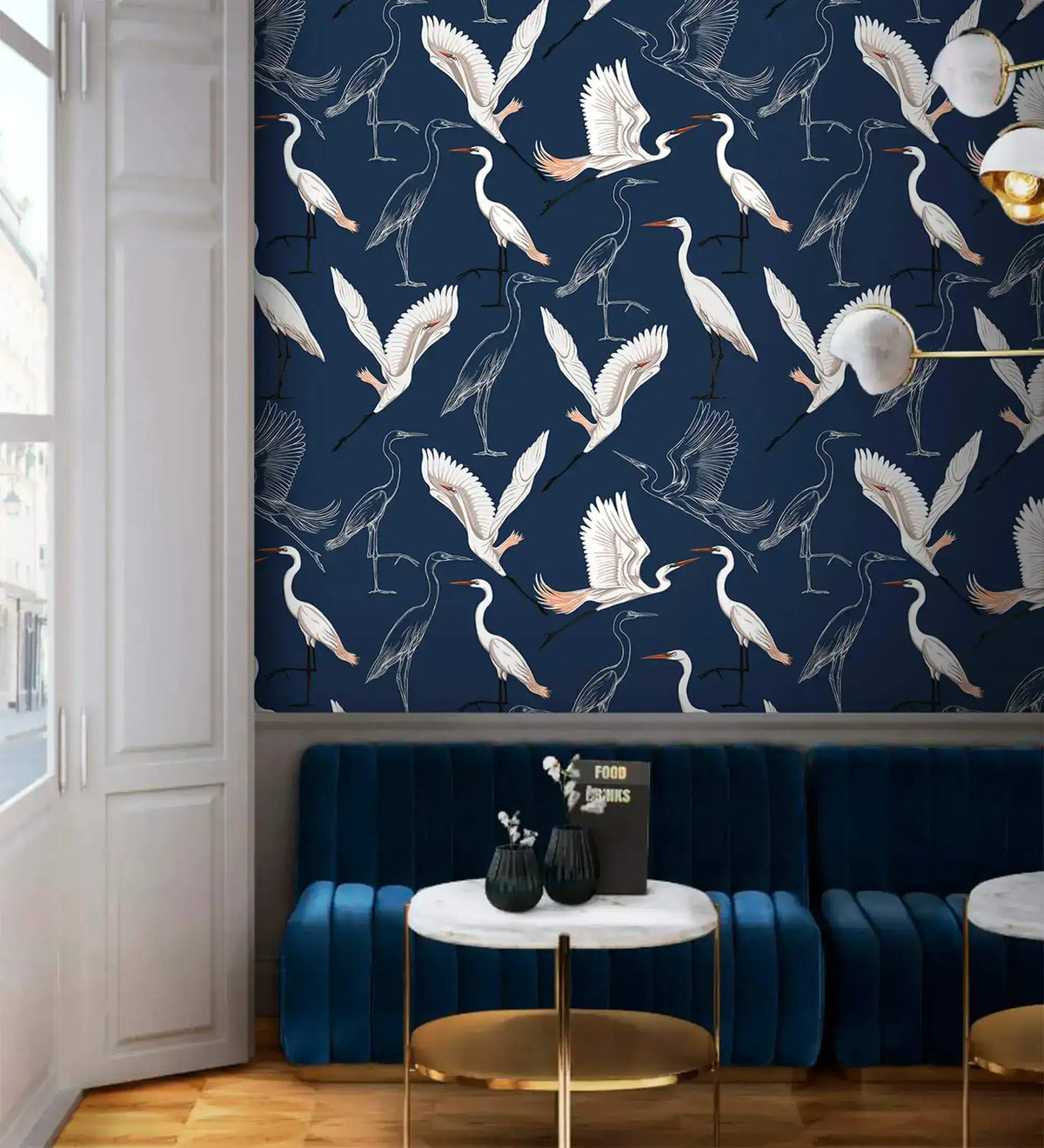 Navy wallpaper with white cranes in cafe nook with blue velvet banquette and marble table