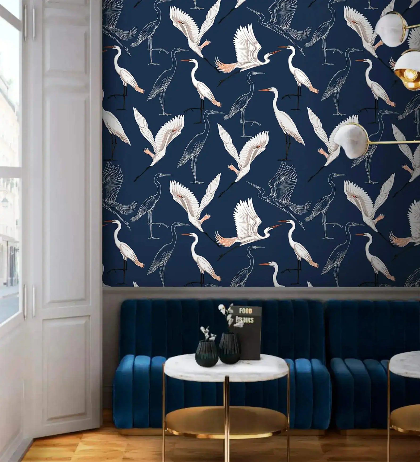 Navy wallpaper with white cranes in cafe nook with blue velvet banquette and marble table