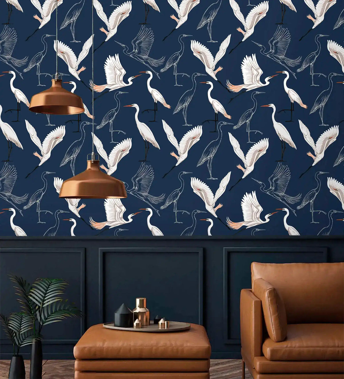 Navy wallpaper with white flying cranes above panelling with copper pendant lamps and tan leather seat