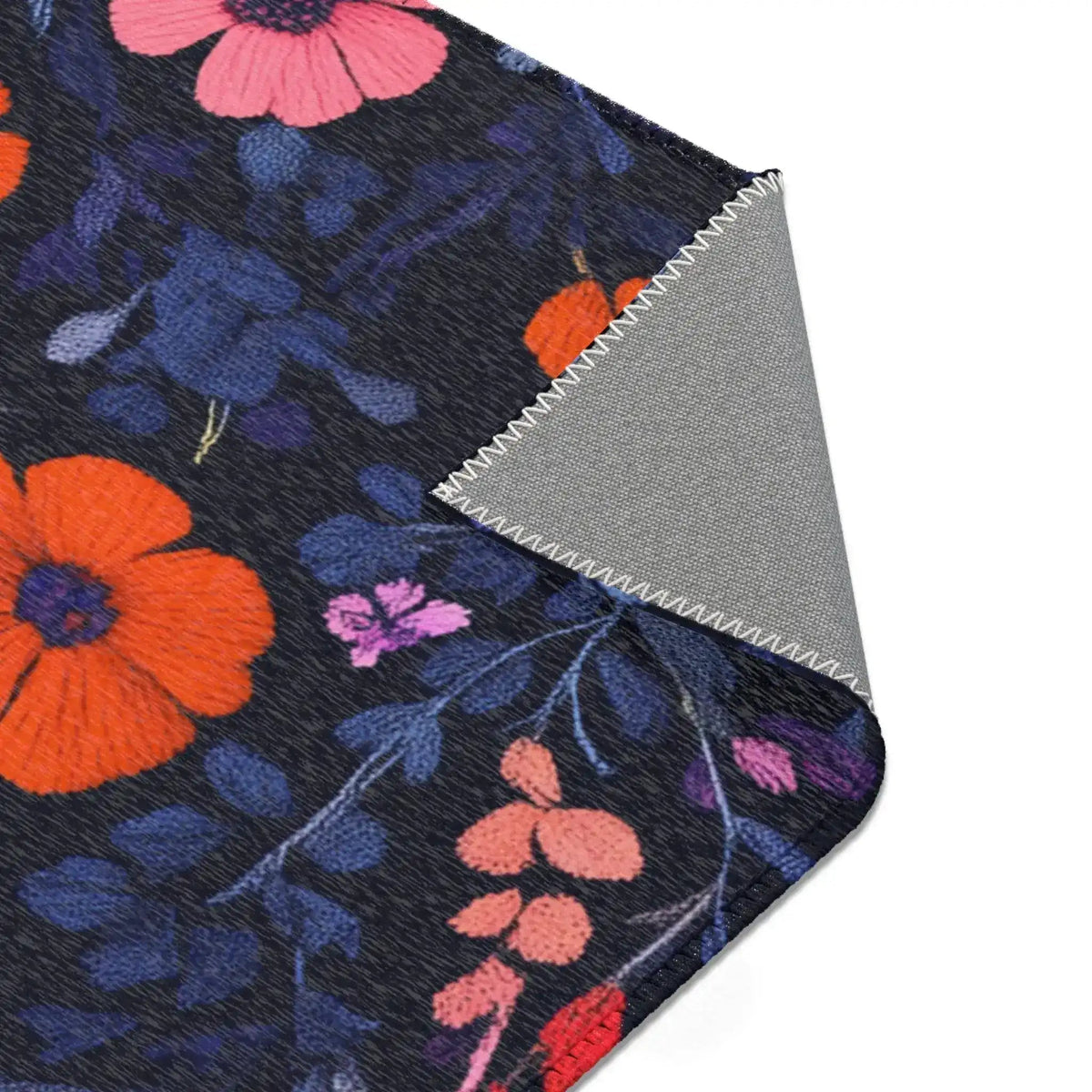 Folded corner of Vibrant Floral Embroidered Accent Rug showing orange and pink flowers on dark navy, angled corner view with grey backing