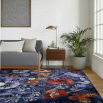 A beautifully vibrant floral area rug adorns a stylish living room, featuring a vivid array of colorful flowers on a deep navy background. This hand-tufted wool rug enhances the modern decor, complementing the sleek gray sofa and wooden side table. Ideal for large living room spaces, this floral rug adds a touch of elegance and warmth.