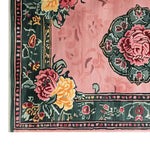 Close-up of the Victorian Bloom Hand Tufted Wool Rug, showcasing its intricate floral patterns in vibrant pinks and yellows on a rich green border. This vintage area rug is perfect for adding a touch of elegance to living room spaces.