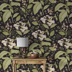 Close-up dark floral wallpaper with white blooms and green leaves behind rustic table with chevron lamp
