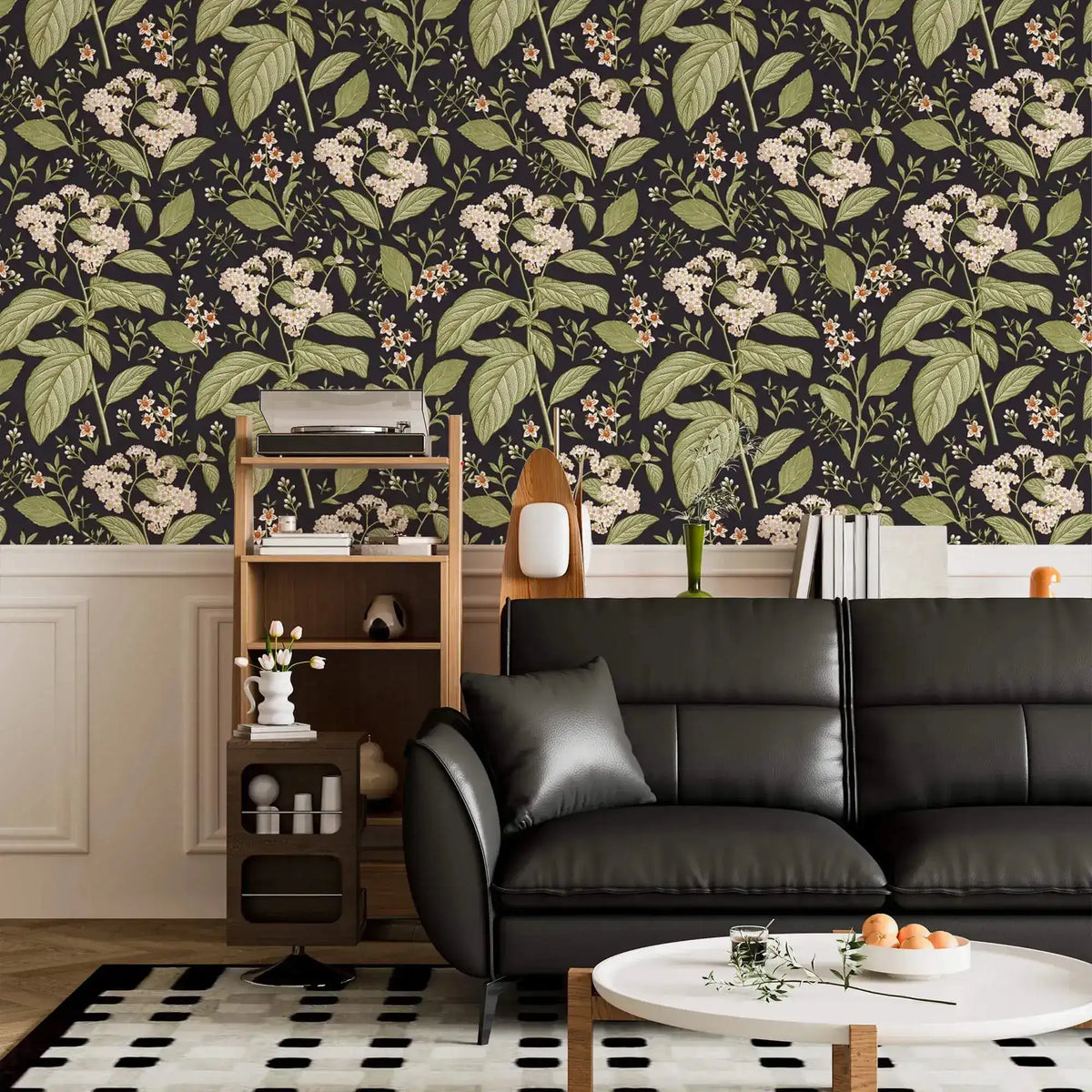 Dark floral wallpaper with white blooms above white panelling with black leather sofa and shelf