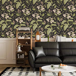 Dark floral wallpaper with white blooms above white panelling with black leather sofa and shelf