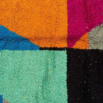 Close-up view of a vibrant Vinai Moroccan Berber handwoven colorful runner rug showcasing bold geometric patterns with rich colors like orange, teal, blue, and pink. Ideal for use as a kitchen rug, wool rug, bathroom runner rug, hallway runner rug, or kitchen runner rug.