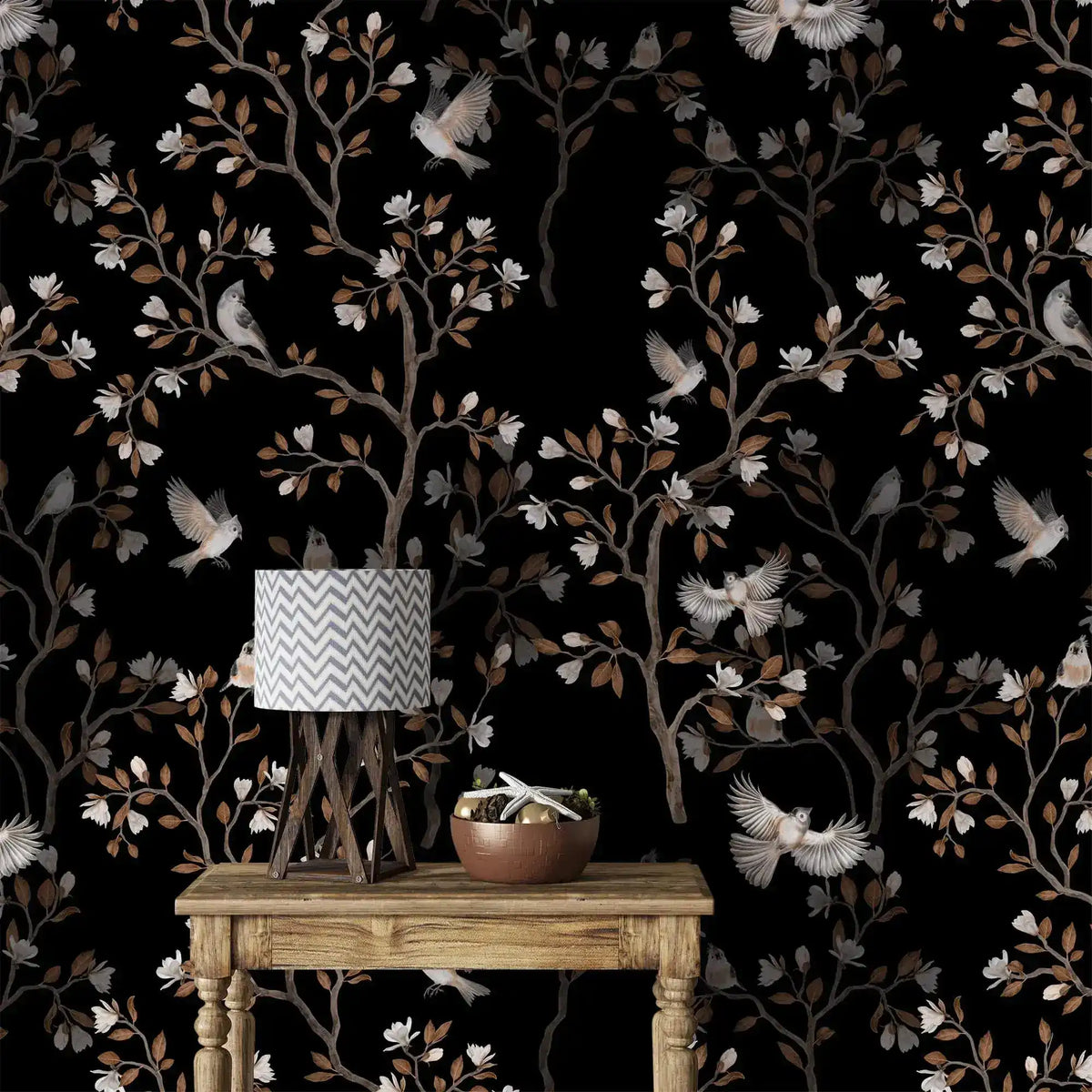 Vintage bird haven wallpaper with birds, blossoms and branches on black behind a rustic wood table and lamp