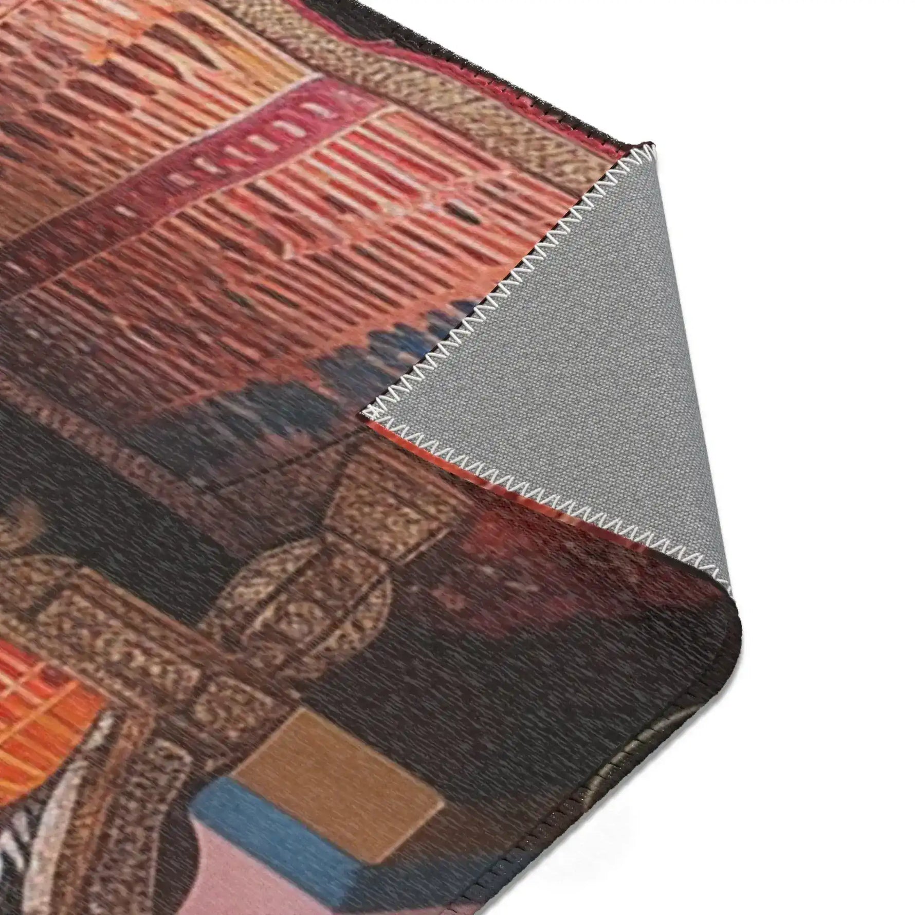 Folded corner of the Vintage Bohemian Woven Rug exposing grey anti-slip backing, rust and dark geometric pattern and carved bench side visible