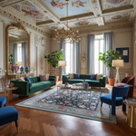 Luxurious living room with green sofas, blue chairs, and decorative elements.