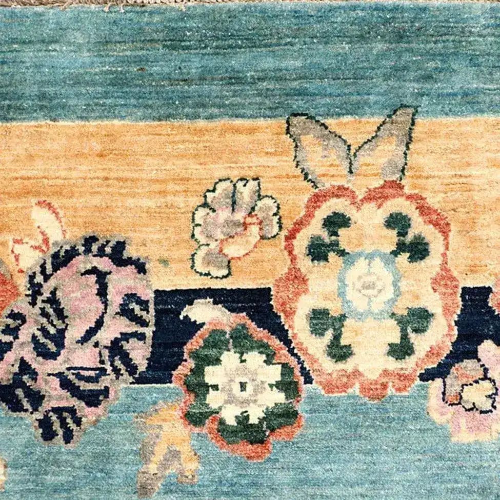 Close-up of a Vintage Floral Bordered Chinoiserie Blue Wool Hand Knotted Area Rug, showcasing intricate floral patterns in vibrant colors on a textured blue background. Ideal for adding elegance to large living room spaces, this living room area rug combines traditional craftsmanship with timeless design.