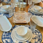 Vintage-Inspired Placemats in blue-white toile set around gold table with crystal glasses and white dishes, full table view