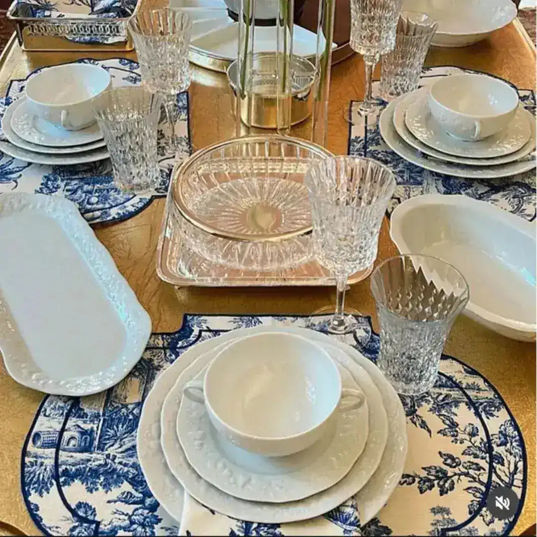 Vintage-Inspired Placemats in blue-white toile set around gold table with crystal glasses and white dishes, full table view