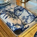 Vintage-Inspired Placemats stacked and folded on silver tray — blue-white toile scenic fabric with navy piped edges