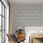 Vintage ornate outline wallpaper in a bedroom, black art deco arches on cream behind an upholstered bed