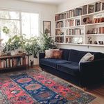 A beautifully styled living room featuring a vintage hand-knotted area rug with vibrant colors, perfect for enhancing any space. The rug's intricate Persian design adds elegance, while its 8x10 size is ideal for living room settings. Surrounded by lush plants, a navy blue sofa, and a bookshelf, this rug is an exquisite choice for those seeking rugs for living room spaces.